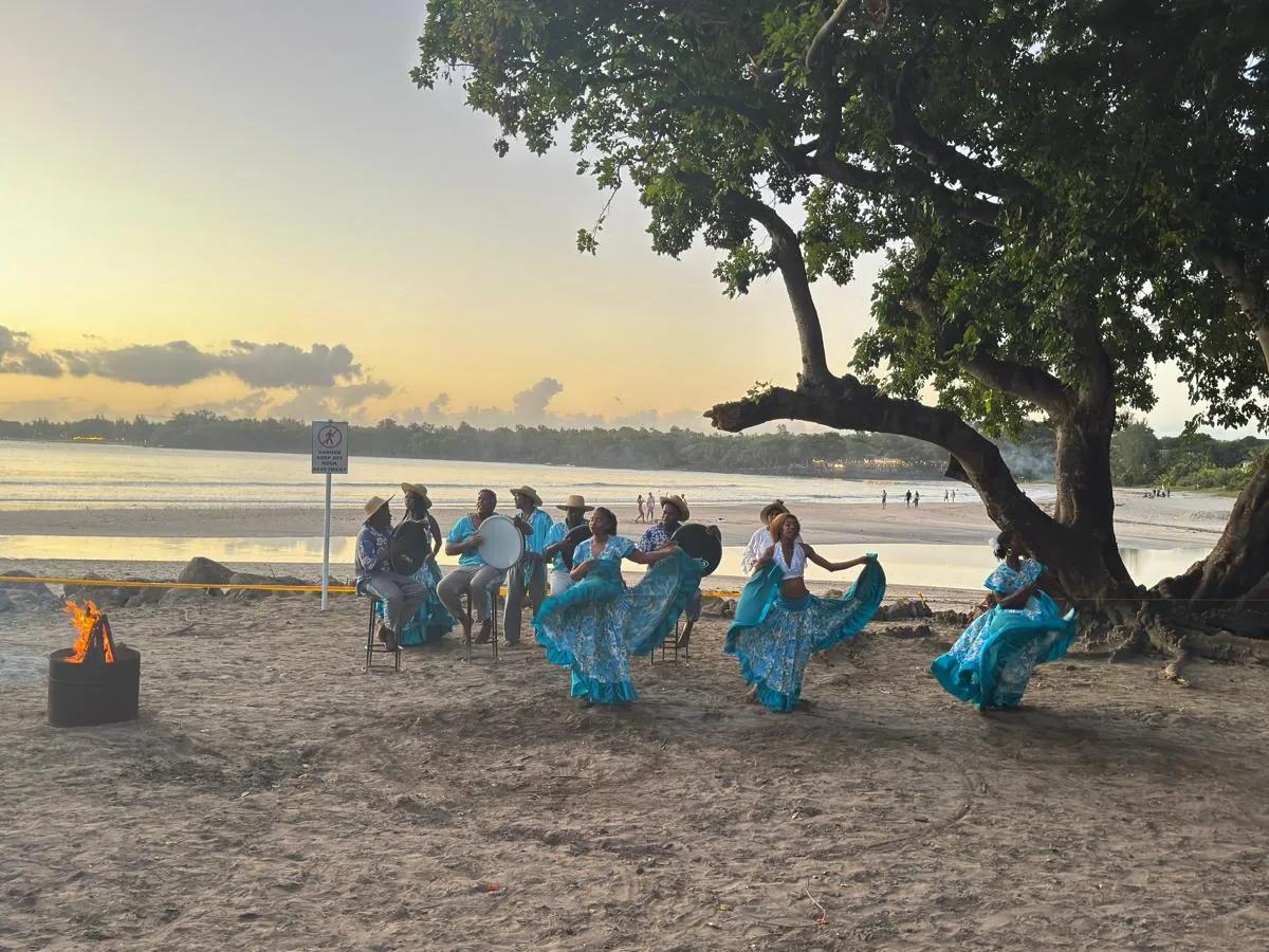 mauritius-sega-dance-performance-by-the-beach-at-sunset--with-musicians-playing-ravanne-drums-under-a-large-coastal-tree-beside-the-lagoon..webp